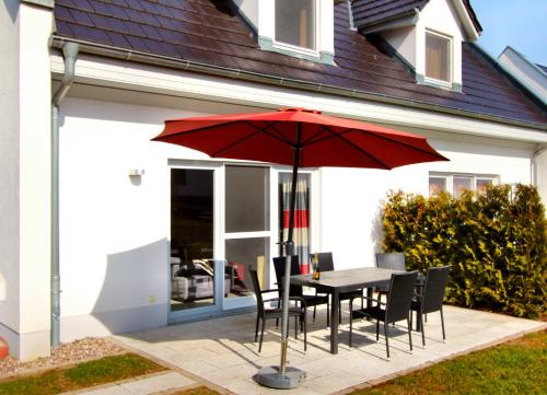ゲーレン・レビンにあるFerien_HAUS FOHLENWEIDEの家の前の赤い傘付きテーブルと椅子