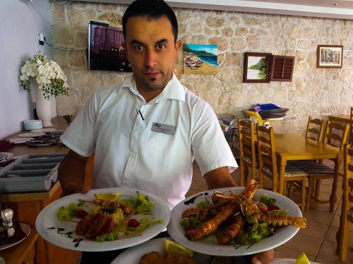 a man is holding two plates of food at Beach Hotel in Drasnice