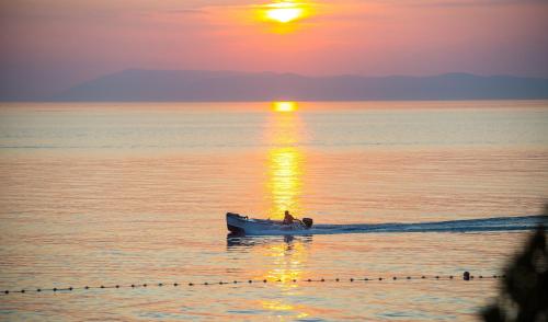 a boat on the water with the sun setting at Beach Hotel in Drasnice