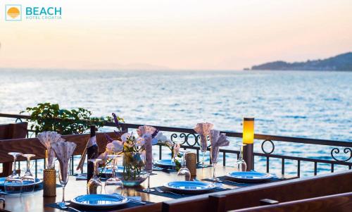 a table with blue plates and flowers on top of the water at Beach Hotel in Drasnice