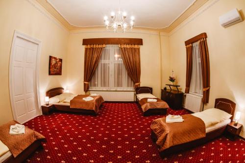 a hotel room with two beds and a red carpet at Hotel Kaskada in Poprad
