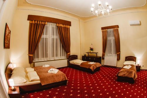 a hotel room with two beds and a chandelier at Hotel Kaskada in Poprad
