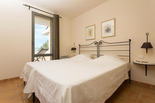 Un dormitorio con una gran cama blanca y una ventana en Madame Vacances Domaine du Provence Country Club Service Premium, en Saumane-de-Vaucluse