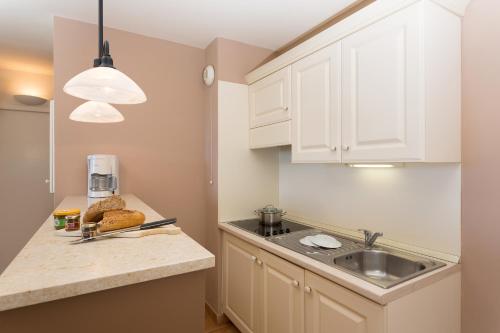una cocina con armarios blancos y fregadero en Madame Vacances Domaine du Provence Country Club Service Premium, en Saumane-de-Vaucluse