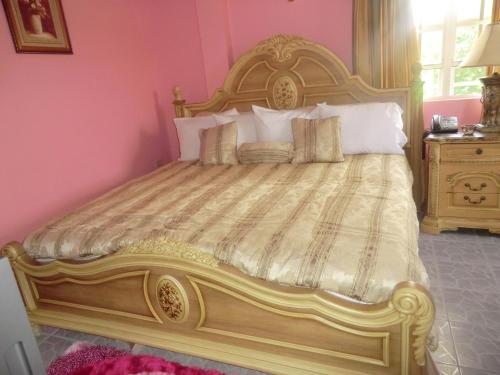 a large bed in a room with pink walls at PG Quality Inn in Georgetown
