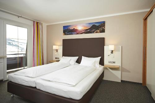 1 dormitorio con 1 cama grande con sábanas blancas en FEWO Schwandenhof, en Bad Hindelang