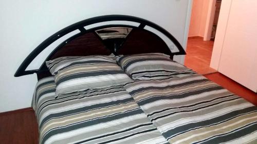 1 cama con cabecero de madera y almohadas en Prle Apartment, en Novi Sad
