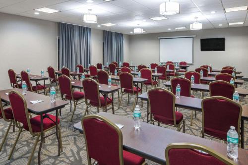 a conference room with tables and chairs and a screen at Comfort Inn & Suites Columbus North in Columbus