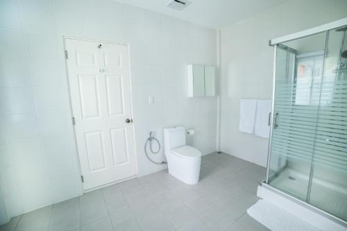 a white bathroom with a toilet and a glass shower at Bohol White House Bed & Breakfast in Lila