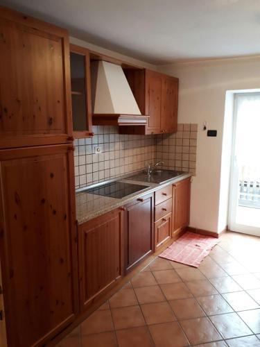 een keuken met houten kasten en een spoelbak bij Ciasa de Anz in Pozza di Fassa