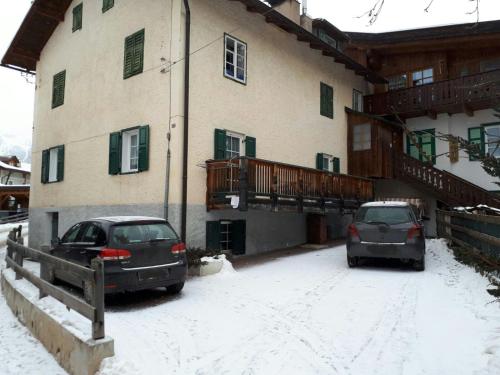 two cars parked outside of a building in the snow at Ciasa de Anz in Pozza di Fassa