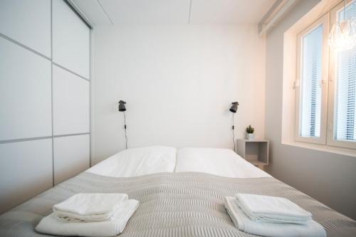 um quarto branco com uma cama com toalhas em Aurora City Center Suite em Rovaniemi