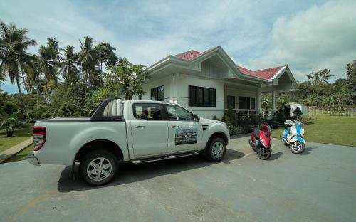 a white truck parked in front of a house with a scooter at Bohol White House Bed & Breakfast in Lila