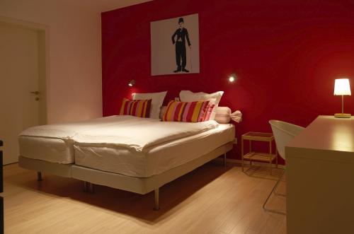 ein Schlafzimmer mit einem weißen Bett und einer roten Wand in der Unterkunft Nena Guesthouse in Löwen