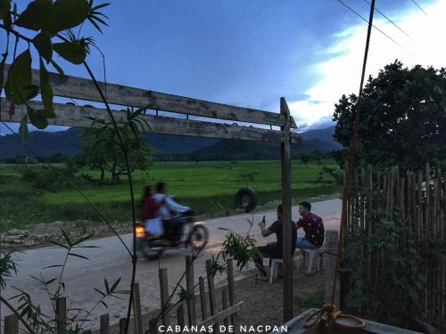 a group of people riding a motor bike down a road at Cabanas de Nacpan Camping Resort in El Nido