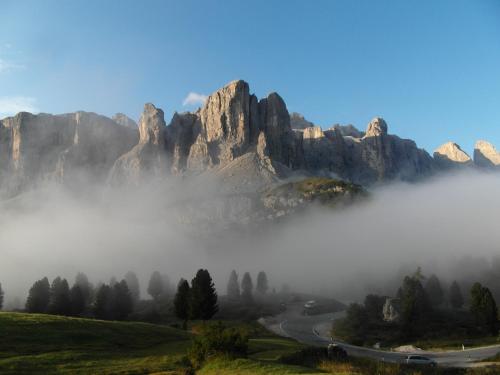 a mountain shrouded in fog with a road in front at Residence Bondì in Colfosco