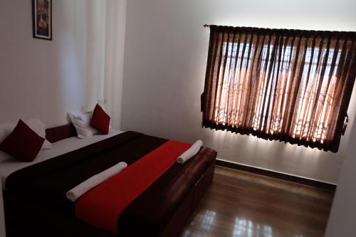 a bedroom with a bed with a red blanket and a window at Rosepark Residency in Ooty