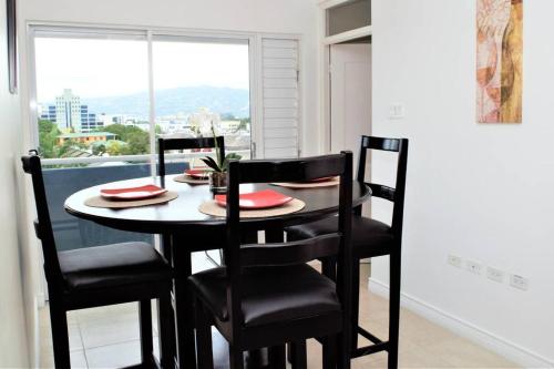 a dining room table with four chairs and a window at The Brompton's Luxury Apartment in Kingston