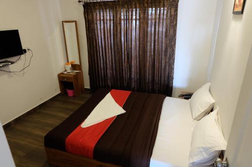 a bedroom with a bed with a colorful blanket and a window at Rosepark Residency in Ooty