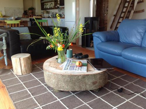 a living room with a table with a vase of flowers at Devon Eco Lodges in Winkleigh
