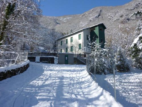 a snow covered road leading to a building in the mountains at Appartements Les Pins in Cierp