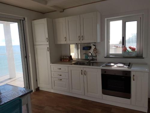 トリーノ・ディ・サングロにあるDimora VaNtoの白いキャビネットとシンク付きのキッチン、窓2つが備わります。