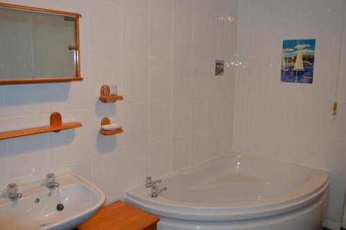 a white bathroom with a tub and a sink at Cruachan in Cellardyke
