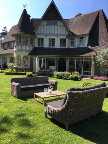a large house with chairs and a table in the yard at Demeure d'Hôtes Haec Otia in Le Touquet-Paris-Plage