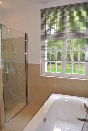 a bathroom with a tub and a shower and a window at Demeure d'Hôtes Haec Otia in Le Touquet-Paris-Plage