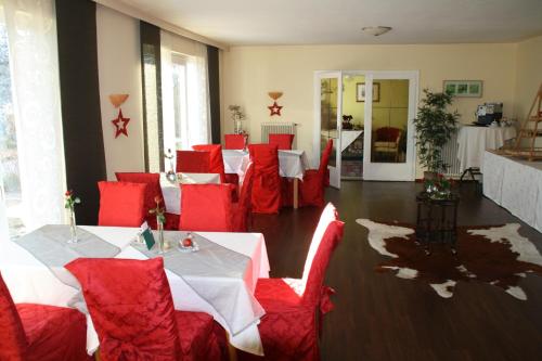 a room with red chairs and tables in a restaurant at Pension Krakolinig in Pörtschach am Wörthersee