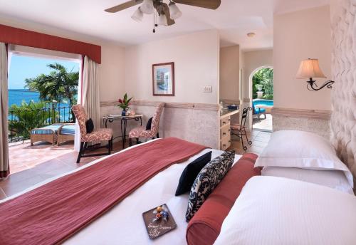 a bedroom with a bed with a view of the ocean at Little Arches Boutique Hotel - Adults Only in Christ Church