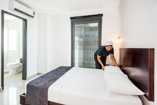 a woman is making a large bed in a room at Ribai Hotels Santa Marta in Santa Marta