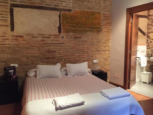 a bed in a room with a brick wall at Hosteria Natura Plaza in Segovia