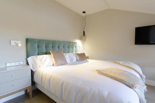 a bedroom with a large white bed with a tv on the wall at Pazo de Mendoza in Baiona