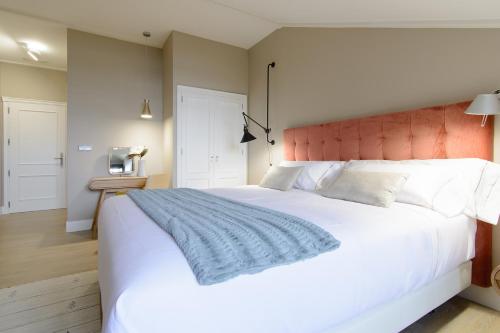 a bedroom with a large white bed with a blue blanket at Pazo de Mendoza in Baiona