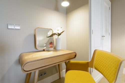 a dressing table with a mirror and a yellow chair at Pazo de Mendoza in Baiona