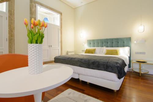 a bedroom with a bed and a vase with flowers on a table at Pazo de Mendoza in Baiona