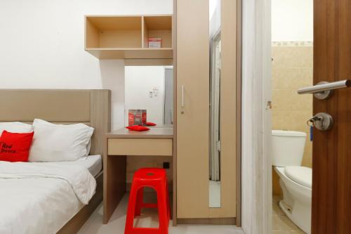 una piccola camera con letto e sgabello rosso di RedDoorz @ Kebon Kacang a Giacarta