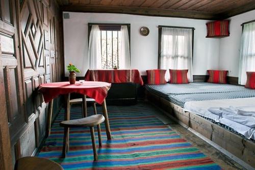 a bedroom with a bed and a table and a table and chairs at Hadjigergy's Guest House in Zheravna