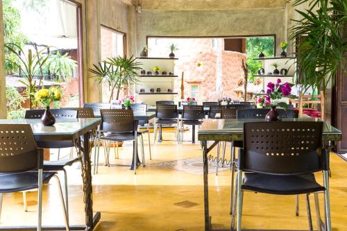 a dining room with tables and chairs and plants at Hern Lhin Natural Resort in Ban Pong