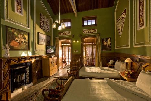 een groene kamer met 2 bedden en een open haard bij WelcomHeritage Fernhills Royal Palace in Ooty