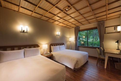 a bedroom with two beds and a desk and a window at Chilan Hotel in Datong