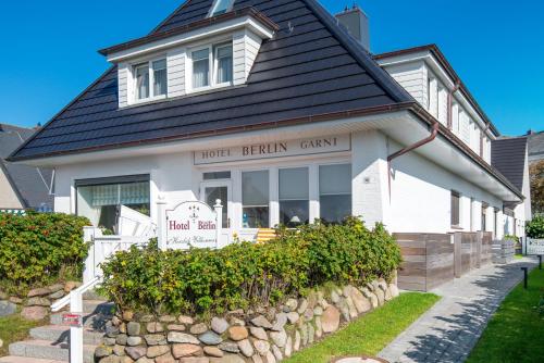a white house with a sign in front of it at Hotel Berlin in Wenningstedt