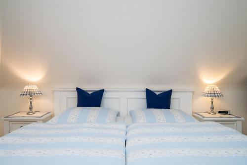 a bedroom with two beds with blue pillows at Hotel Berlin in Wenningstedt