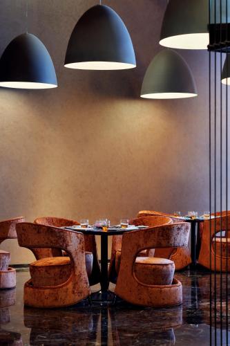a dining room with tables and chairs and pendant lights at Southern Sun Abu Dhabi in Abu Dhabi