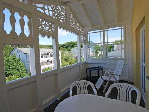 uma varanda com uma mesa, cadeiras e janelas em Villa Freya - Apt. 06 em Ostseebad Sellin