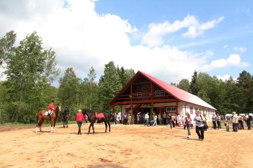 a group of people standing around a barn with horses at Zirgu sēta "Klajumi" - Horse ranch "Klajumi" in Kaplava