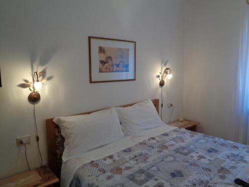 a bedroom with a bed with two lights on the wall at Casa Noemi Imer in Imer