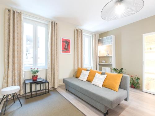 - un salon avec un canapé gris et des oreillers jaunes dans l'établissement Charme au cœur d'avignon, à Avignon