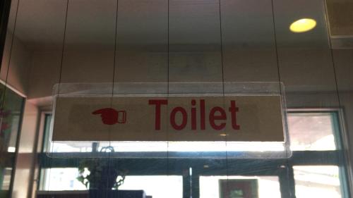 a sign for a toilet hanging in front of a window at Kagoshima Little Asia in Kagoshima